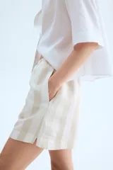 Short de lino y viscosa color crudo con rayas verticales en tono beige. Tiene cintura elástica con cordón ajustable y bolsillos laterales.