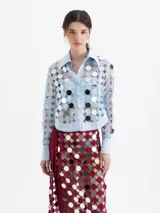 Camisa de manga larga color celeste claro, confeccionada en guipur con apliques circulares espejados. Posee cuello y puños en tela lisa y cierre frontal con broches snap forrados. Incluye un top interno liso al tono.