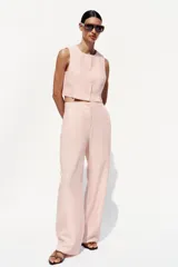 Pantalón de vestir color rosa pálido, de tiro alto, con pinzas delanteras, bolsillos laterales, pierna ancha y cierre frontal con cremallera y botón.