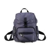 Mochila negra de nylon con tapa y broche metálico. Tiene apertura superior con broche, bolsillos internos, bolsillo con cierre metálico al frente y laterales. Tiene asas rígidas de mano y correas regulables para colgar en la espalda.