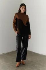 Buzo de punto con diseño geométrico en bloques de color gris y negro, de cuello redondo y mangas largas.