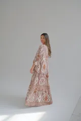 Vestido largo color rosa con estampado floral y geométrico en tonos blanco y naranja. Tiene cuello mao, mangas 3/4 y corte escalonado en la falda.