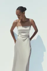 Vestido midi de satén color gris claro, con escote recto, tirantes finos regulables, cuerpo tipo pañuelo con terminación en pico, espalda descubierta con lazo y cierre lateral con cremallera oculta.