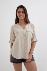 Camisa color beige de algodón con escote en V, mangas 3/4 con trabillas y dos bolsillos de parche en el pecho.