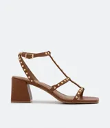 Sandalias marrones con tiras finas y remaches dorados, puntera cuadrada, cierre con hebilla en el tobillo y tacón bloque.