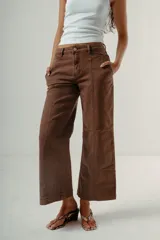 Pantalón de denim color marrón oscuro, tiro medio, con silueta wide leg y costuras verticales marcadas en el frente de ambas piernas.