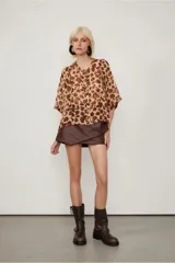 Camisa de manga corta con estampado animal print, cuello bote, abotonada en el frente y de fit amplio.