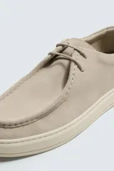 Zapato casual de cordones color beige, con parte superior de piel serraje, detalle de bordón en el empeine y suela a contraste.