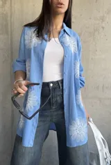Camisa celeste de manga larga con bordados de flores blancas.