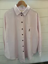 Camisa rosada de tela oxford con bordado de árbol en el bolsillo y botones marrones. Corte oversized.