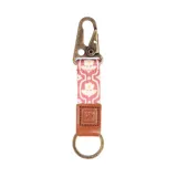 Llavero con mosquetón metálico color bronce, cinta de tela estampada con flores en tonos rosa y blanco, pieza de cuero marrón con logo grabado y aro metálico color bronce.