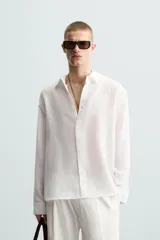 Camisa de manga larga color celeste claro, con cuello solapa y cierre frontal de botonadura. Presenta una textura sutil en el tejido.