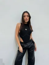 Body negro de lycra con cuello alto, corte cavado y logo metálico en el pecho.