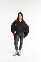 Camisa color beige de satén con corte holgado, cuello camisero y mangas largas con puños abotonados.