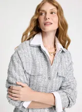 Parca gris de malla con bordado de lentejuelas, corte ajustado, cuello camisero, cierre frontal con botones, dos bolsillos decorativos, cintura con cordón, mangas largas y largo extra.