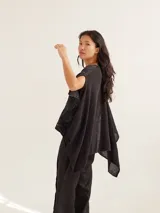 Poncho liviano color negro con brillo sutil y corte asimétrico, diseñado para aportar elegancia.
