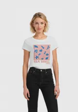 Remera blanca de algodón con estampado de conchas marinas en tonos azules sobre un fondo rosa.