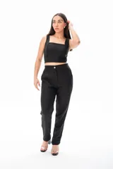 Conjunto negro de top corto con breteles anchos y pantalón de vestir de tiro alto con botón dorado.