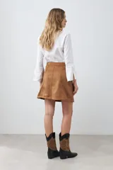 Minifalda color tostado de simil gamuza, corte recto y cierre trasero invisible.