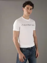 Remera blanca de algodón con cuello redondo y mangas cortas. Estampado frontal con el logo "Calvin Klein Jeans" en color negro.