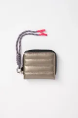 Billetera beige con diseño capitoneado y cierre de cremallera. Incluye cordón trenzado multicolor con terminales plásticas rosas.