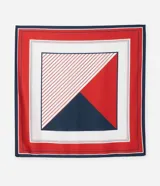 Pañuelo cuadrado de satén con diseño geométrico en bloques de color rojo, blanco y azul marino. La sección blanca presenta un patrón de rayas diagonales finas en rojo. El pañuelo tiene un borde exterior en azul marino y un borde interior en rojo.