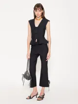 Pantalón negro con cintura rebatida y cierre lateral. Diseño entallado con pinzas delanteras y traseras, corte flare y tajo en el ruedo con moño.