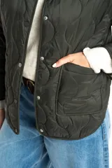 Campera acolchada color verde militar, con cuello redondo y cierre frontal de broches a presión. Presenta un patrón de costuras onduladas.