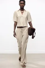 Pantalón de tiro alto color beige, con cintura elástica ajustable con cordones, bolsillos delanteros y pernera ancha.