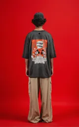 Remera de algodón premium, color gris oscuro con efecto lavado, corte oversize y manga corta. Presenta un pequeño estampado frontal de Mickey Mouse en un recuadro naranja.