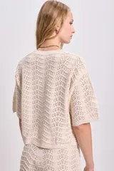 Top de punto crochet color crudo con mangas cortas y cuello redondo.
