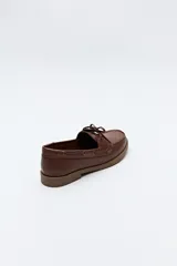 Zapato náutico color beige, de símil cuero, con cordones y suela marrón antideslizante.