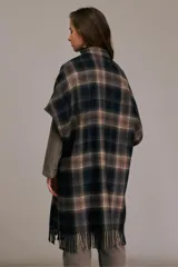 Tapado tipo capa con mangas tres cuartos, confeccionado en mezcla de lana a cuadros en tonos negro, azul, caqui y chocolate. Presenta cuello pequeño con cierre de botón, cierre cruzado con cinturón de tela a juego, mangas anchas hasta el codo, corte holgado y dobladillo con flecos.