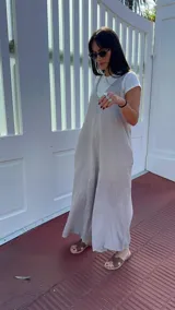 Mono largo de lino color beige, con breteles finos ajustables que se atan en la espalda, corte holgado y bolsillos laterales.