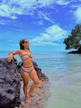 Bombacha de bikini tiro alto con estampado floral en tonos naranja, rojo y verde, con ribete negro.