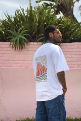 Remera color beige de manga corta con cuello redondo y estampado de un sol con montañas en el pecho.
