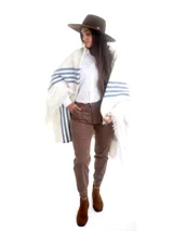 Poncho blanco de hilo de algodón grueso con flecos y escudo nacional uruguayo bordado en la espalda. Presenta franjas horizontales azules en los laterales.