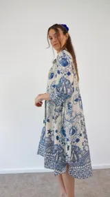 Vestido camisero de manga larga, color blanco con estampado azul de motivos marinos como medusas, conchas y corales. Tiene cuello camisero y bolsillos laterales.