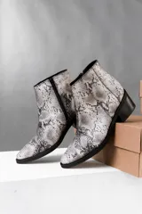 Botas cortas de cuero vacuno color marrón con estampado de piel de serpiente, taco de madera foliado en cuero y cierre lateral con cremallera.