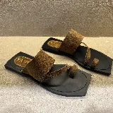 Sandalias planas de cuero color marrón con base negra, con tira ancha sobre el empeine y tira fina entre los dedos.