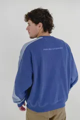 Buzo azul con mangas raglán en tono celeste y puños ajustados. Estampa frontal con la palabra "CONFIDENTIAL" en mayúsculas.
