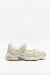 Zapatilla deportiva color beige con suela confortable de 4cm de alto y tira ajustable con velcro.