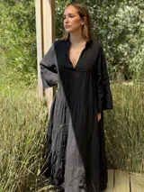 Vestido largo negro de lino, con cuello mao, escote en V, mangas largas acampanadas y corte escalonado.
