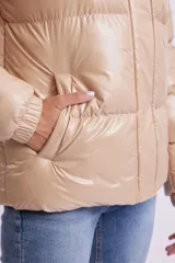 Campera puffer color beige de poliéster con capucha, cierre frontal con cremallera y bolsillos laterales.
