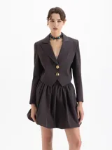 Saco blazer cropped color marrón con rayas finas, confeccionado en lanita. Presenta solapa en pico profunda, hombreras y cierre frontal con dos botones dorados.