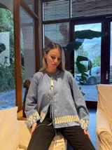 Camisa celeste con bordado floral blanco en el ruedo y los puños, con cierre frontal con lazos. 