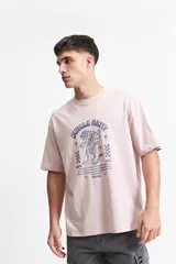 Remera color rosa claro de corte oversize y mangas cortas. Estampado frontal con la leyenda "Jungle Army", un tigre y otros símbolos.