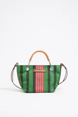 Bolso tote pequeño de lona a rayas verdes, negras, rosas y beige. Tiene doble asa de mano de madera y correa fina de cuero sintético marrón. Incluye logo de la marca en etiqueta verde cosida al frente.