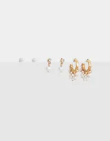 Set de tres pares de aros dorados: un par de aros pasantes con perlas, un par de aros con dije de corazón con perla y un par de argollas con colgantes de perlas.