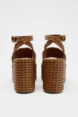 Sandalias con plataforma tipo cuña color marrón, con cuerpo trenzado, tira delantera y cierre mediante tira con hebilla a la pulsera del tobillo.